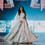 JTorry South Asian bridal reception look: bride dancing in white-gold lehenga on stage
