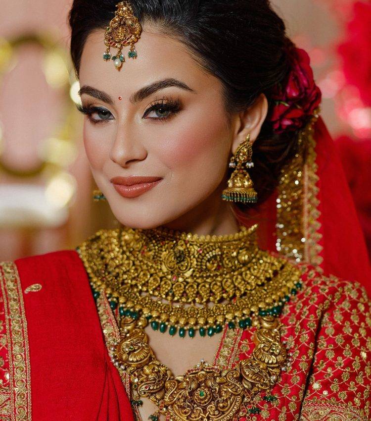 JTorry bride in a red bridal outfit with gold jewelry and a maang tikka