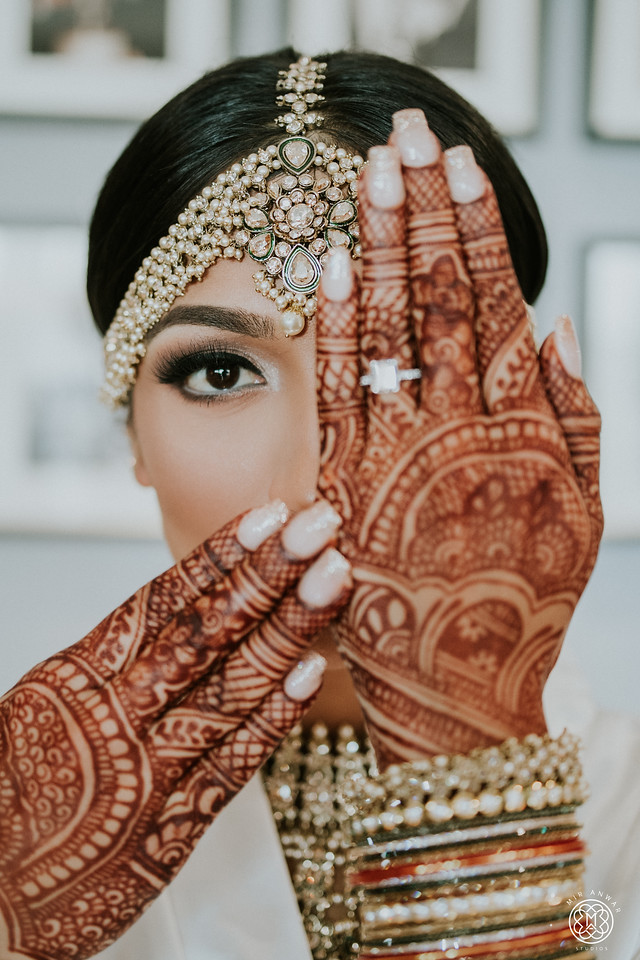 JTorry bride with intricate henna, bangles, bridal makeup and a jeweled headpiece